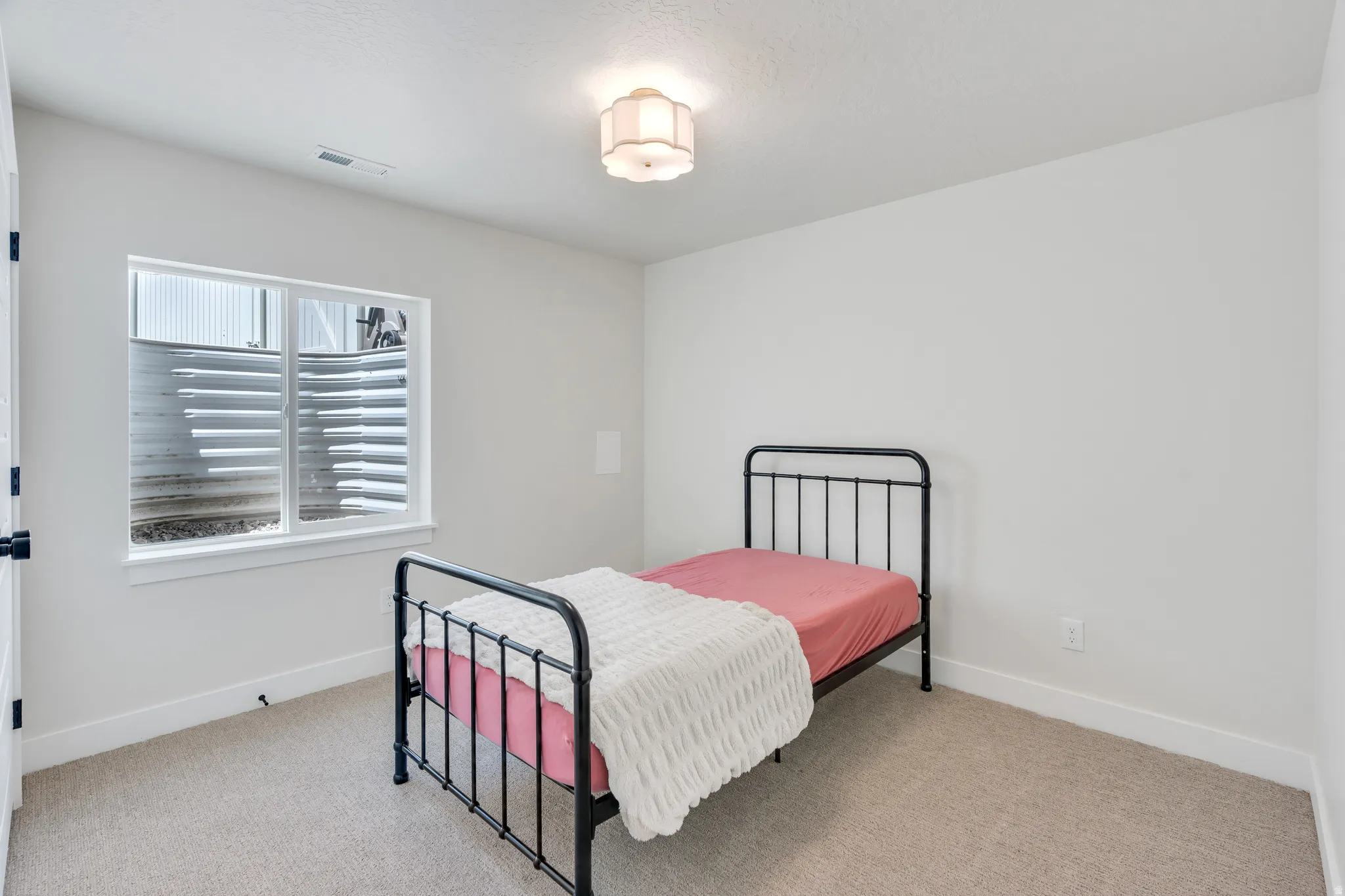 Recessed window with white trim, light neutral carpet, white painted walls, and a decorative ceiling light fixture