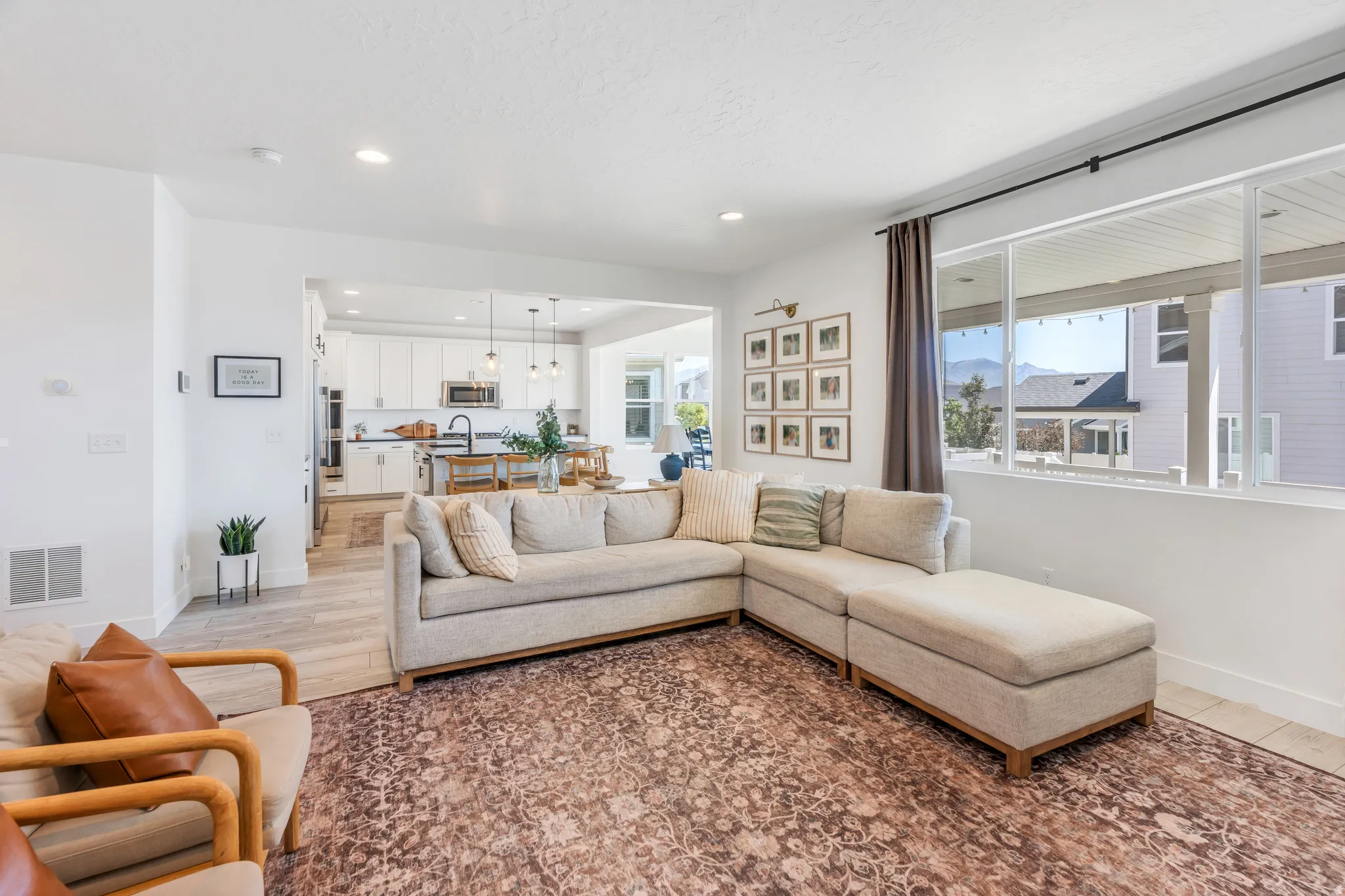 Open-concept living space featuring light wood-finish flooring, recessed lighting, and a large picture window