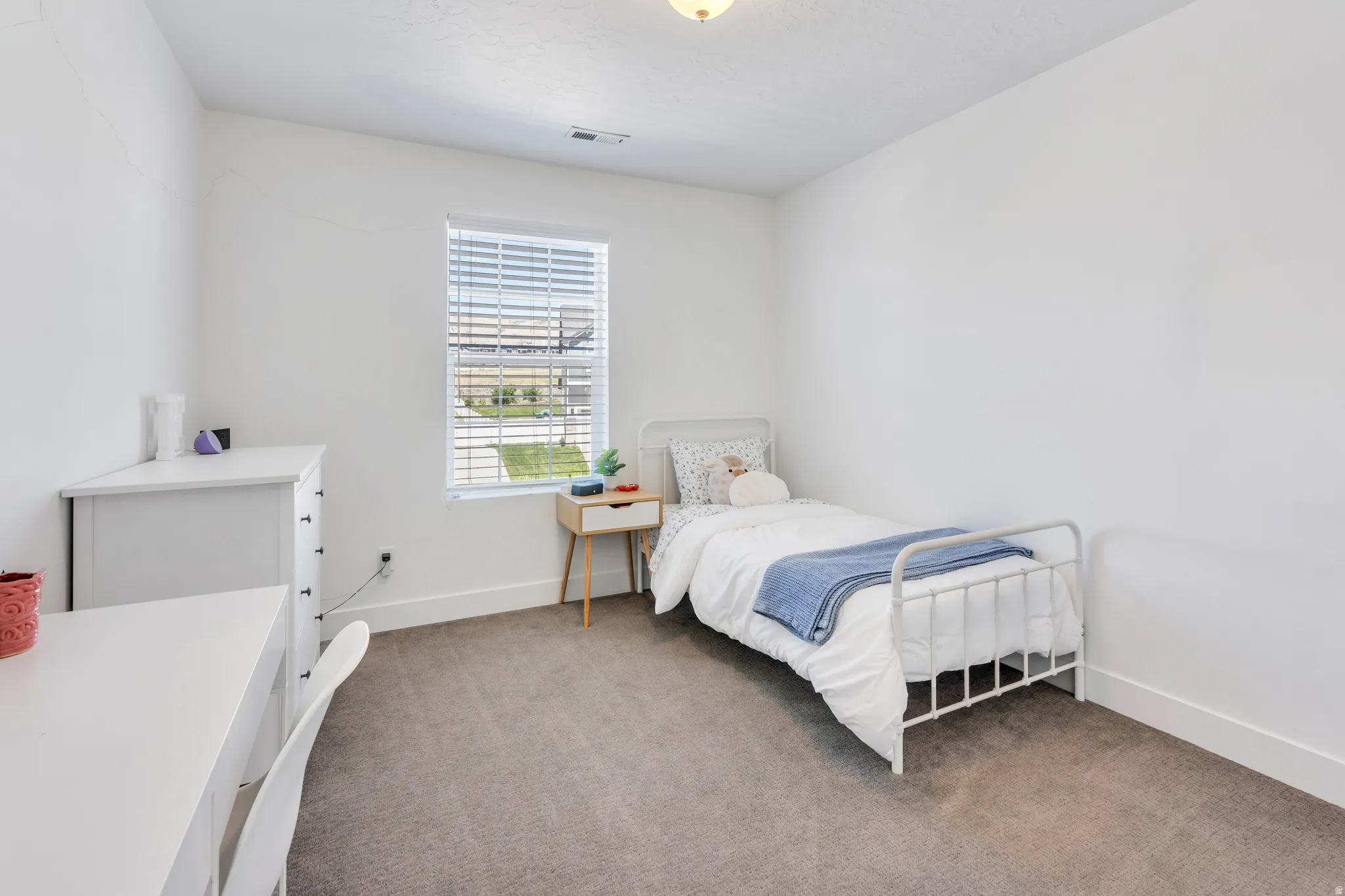 Carpeted room with a single window featuring blinds
