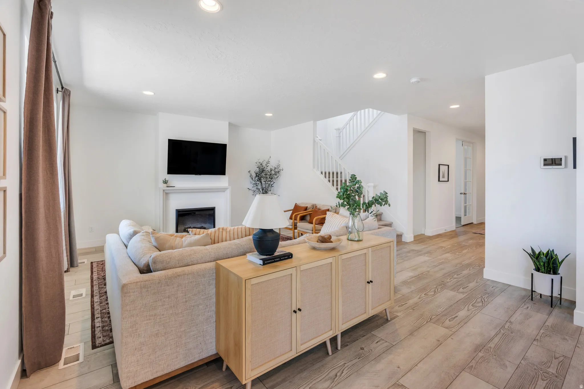 Open concept living area featuring wood-finish flooring, recessed lighting, and a fireplace with a white mantel