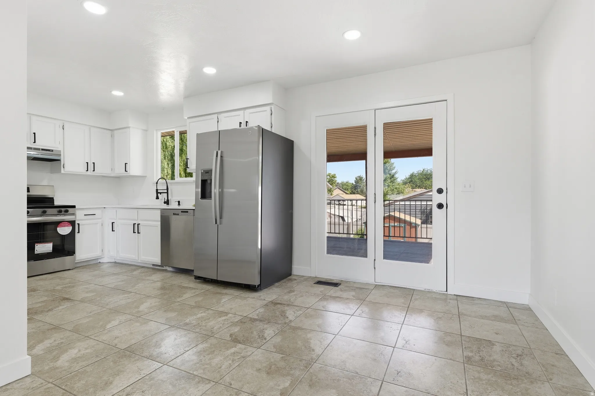 Bright kitchen featuring white cabinetry, stainless steel appliances, recessed lighting, and tile flooring