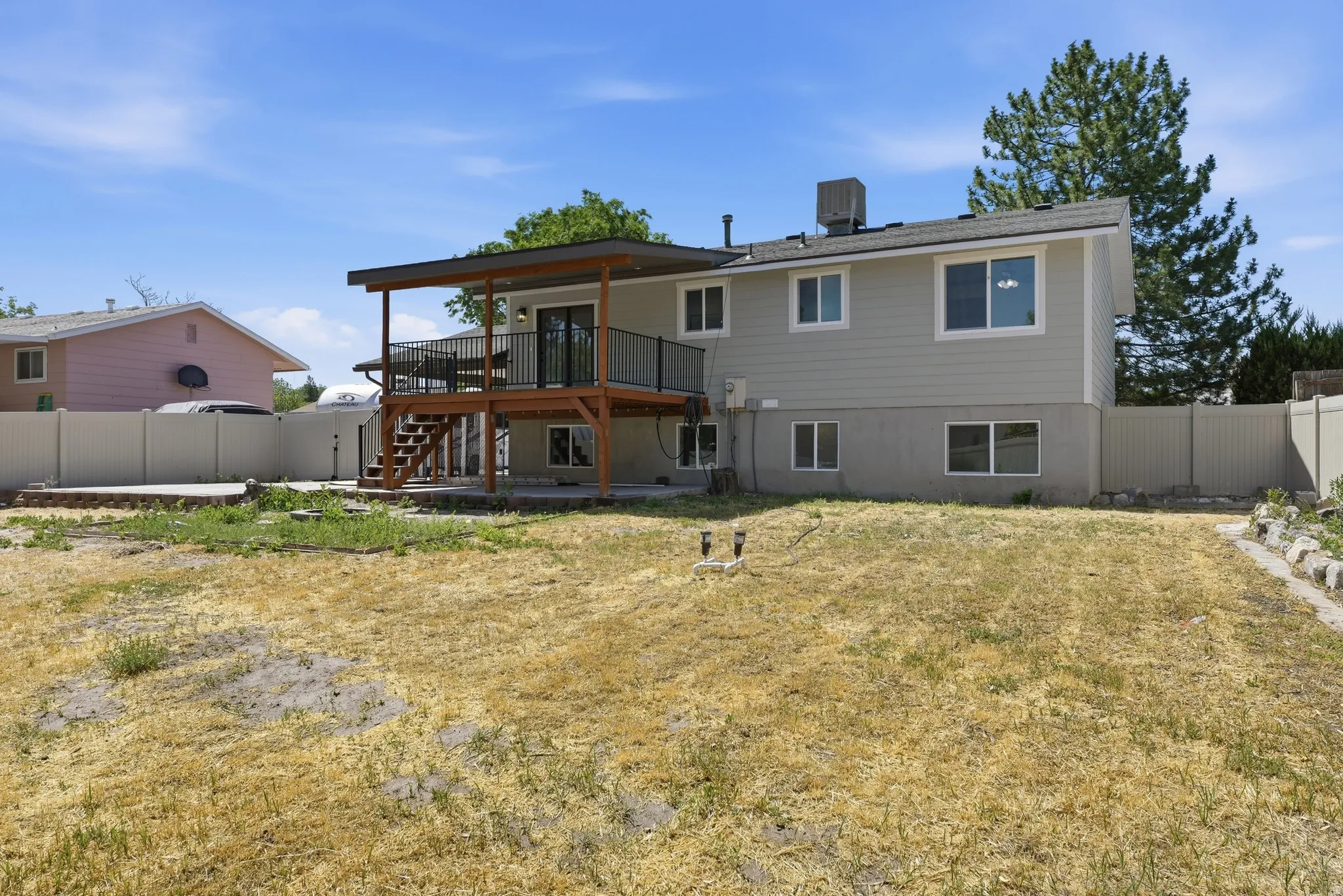 Spacious rear yard with a covered wooden deck, black metal railings, and a walk-out lower level