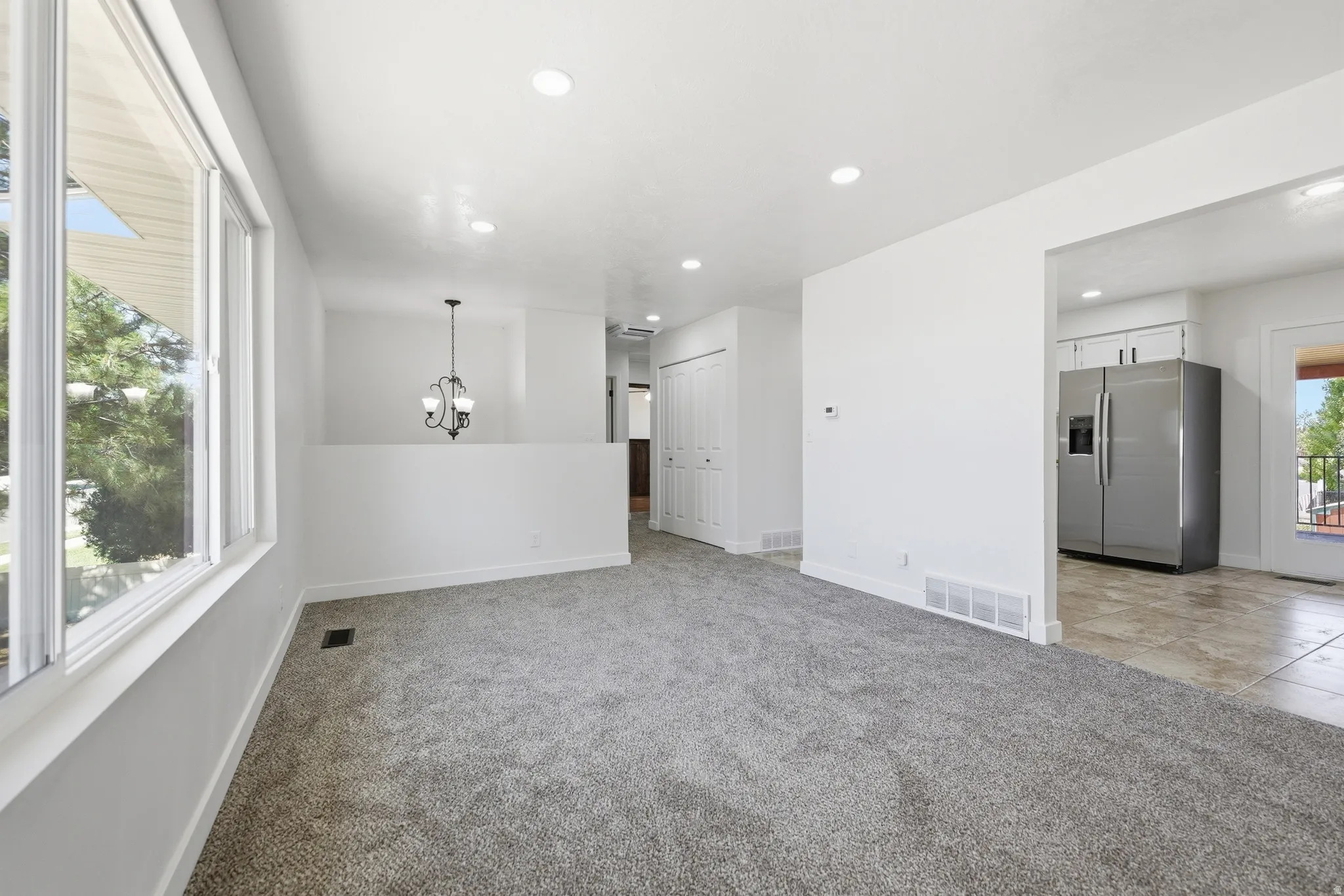 Spacious room featuring neutral carpeting, recessed lighting, and a large multi-pane window
