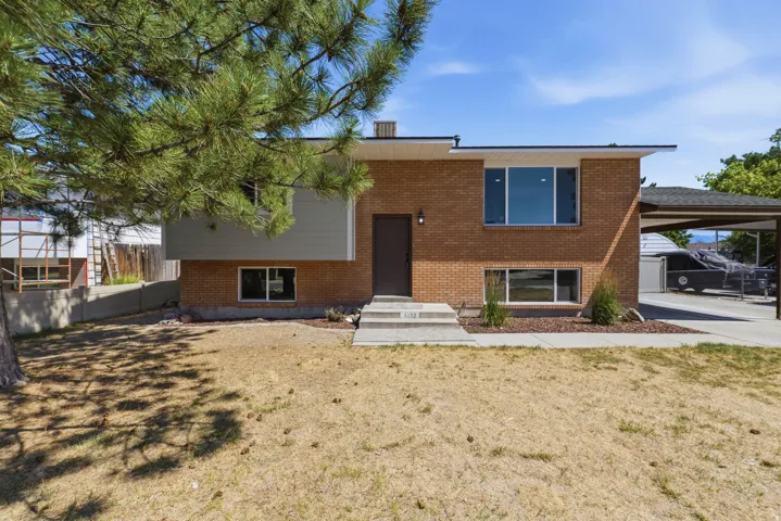 Brick exterior with contemporary siding accents, a concrete walkway, and a covered carport