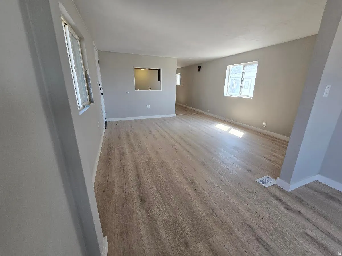 Spacious interior featuring wood-finish flooring, light gray wall paint, white trim, and multiple windows