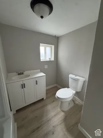 White vanity with a solid surface countertop, undermount sink, and matte black hardware, paired with wood-finish flooring and a dome ceiling light fixture