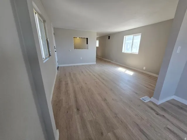 Spacious interior featuring wood-finish flooring, light gray wall paint, white trim, and multiple windows