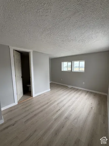 Room featuring wood-finish flooring, neutral wall paint, a textured ceiling, and dual double-pane windows