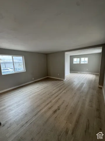 Interior space featuring wood-finish flooring, neutral wall paint, and multiple windows providing natural light