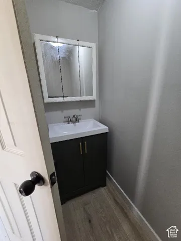 Bathroom vanity featuring a white sink basin and a dark cabinet with gold-toned hardware