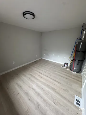 Neutral-toned walls paired with light-toned wood-finish flooring and a contemporary circular flush-mount ceiling light