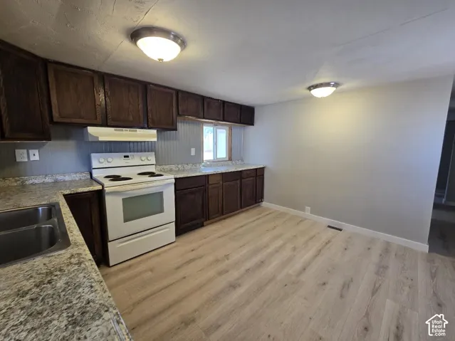 Kitchen featuring wood-finish flooring, dark wood cabinetry, and speckled countertops