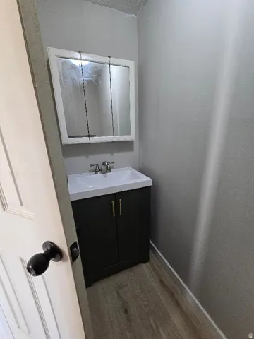 Bathroom vanity featuring a white sink basin and a dark cabinet with gold-toned hardware