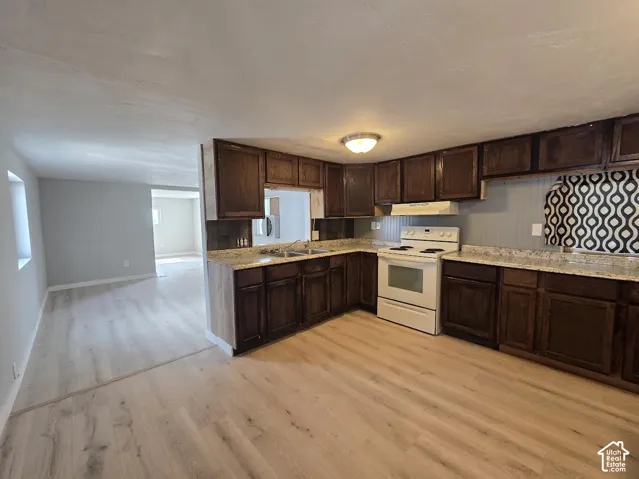 Kitchen featuring dark wood cabinetry, light-toned countertops, and an electric range with overhead ventilation