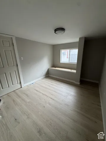 Neutral-toned interior featuring wood-finish flooring, a built-in window bench, and a flush-mount ceiling light fixture