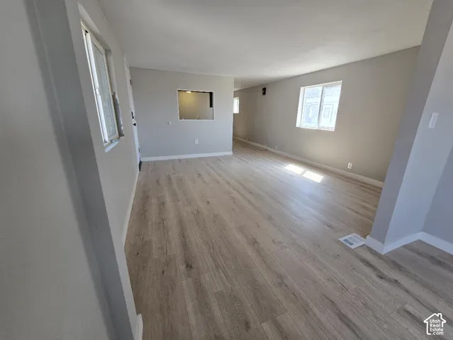 Spacious interior featuring wood-finish flooring, light gray wall paint, white trim, and multiple windows