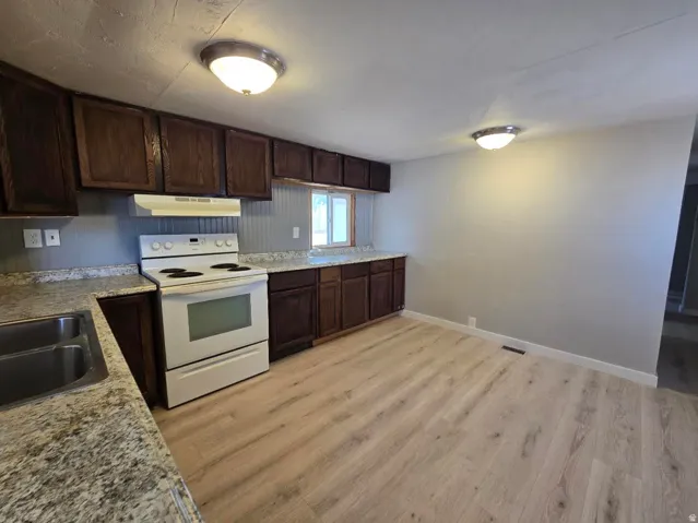 Kitchen featuring wood-finish flooring, dark wood cabinetry, and speckled countertops