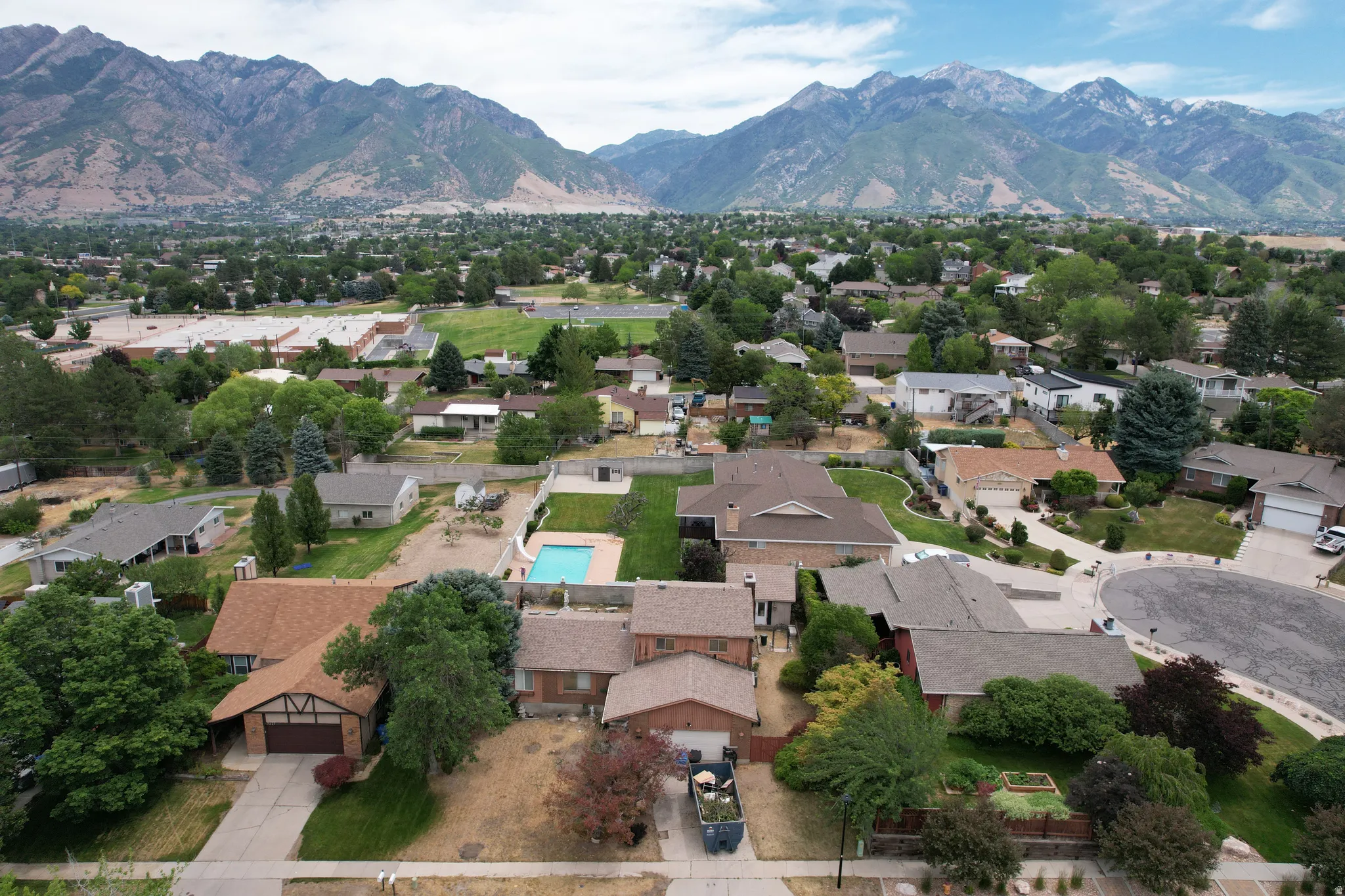 Expansive residential area featuring numerous single-family homes, mature tree coverage, and a distant mountain range backdrop
