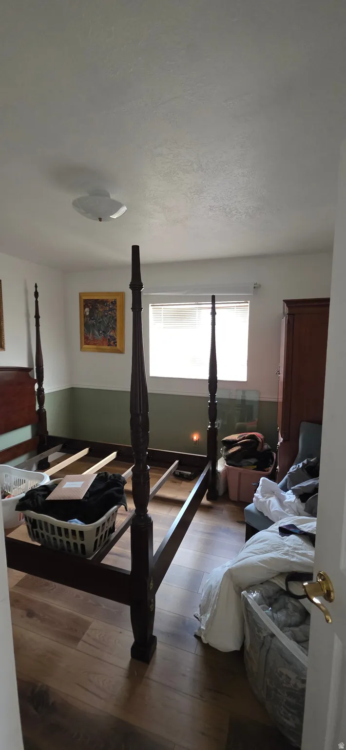 Bedroom featuring wood-finish flooring, a window with blinds, and two-tone wall treatment