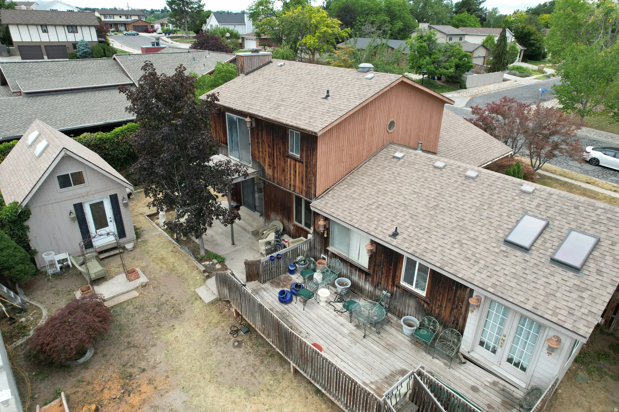 Expansive rear exterior featuring a multi-level wood deck, a detached shed with skylights, and mature landscaping