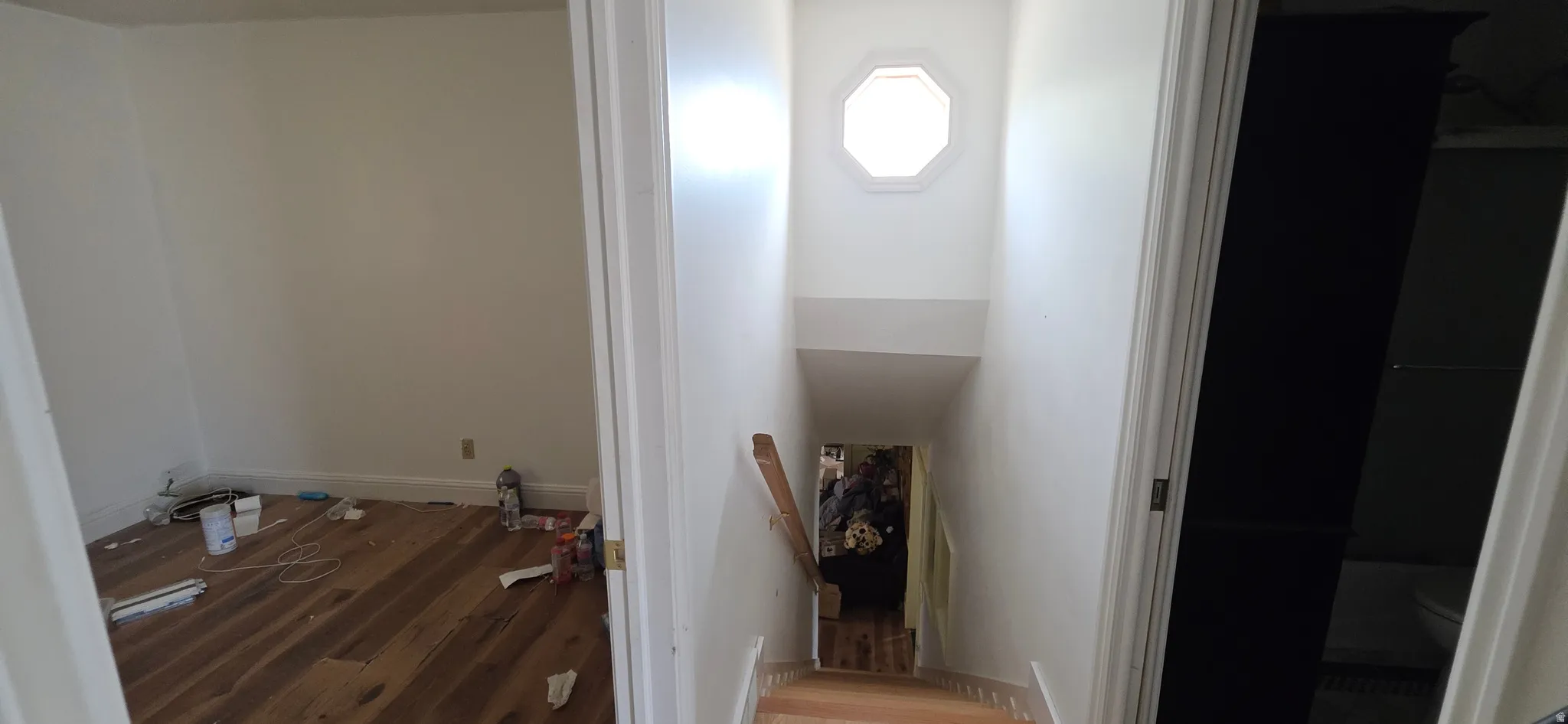 Stairwell featuring an octagonal window, natural wood handrail, and wood-finish stair treads