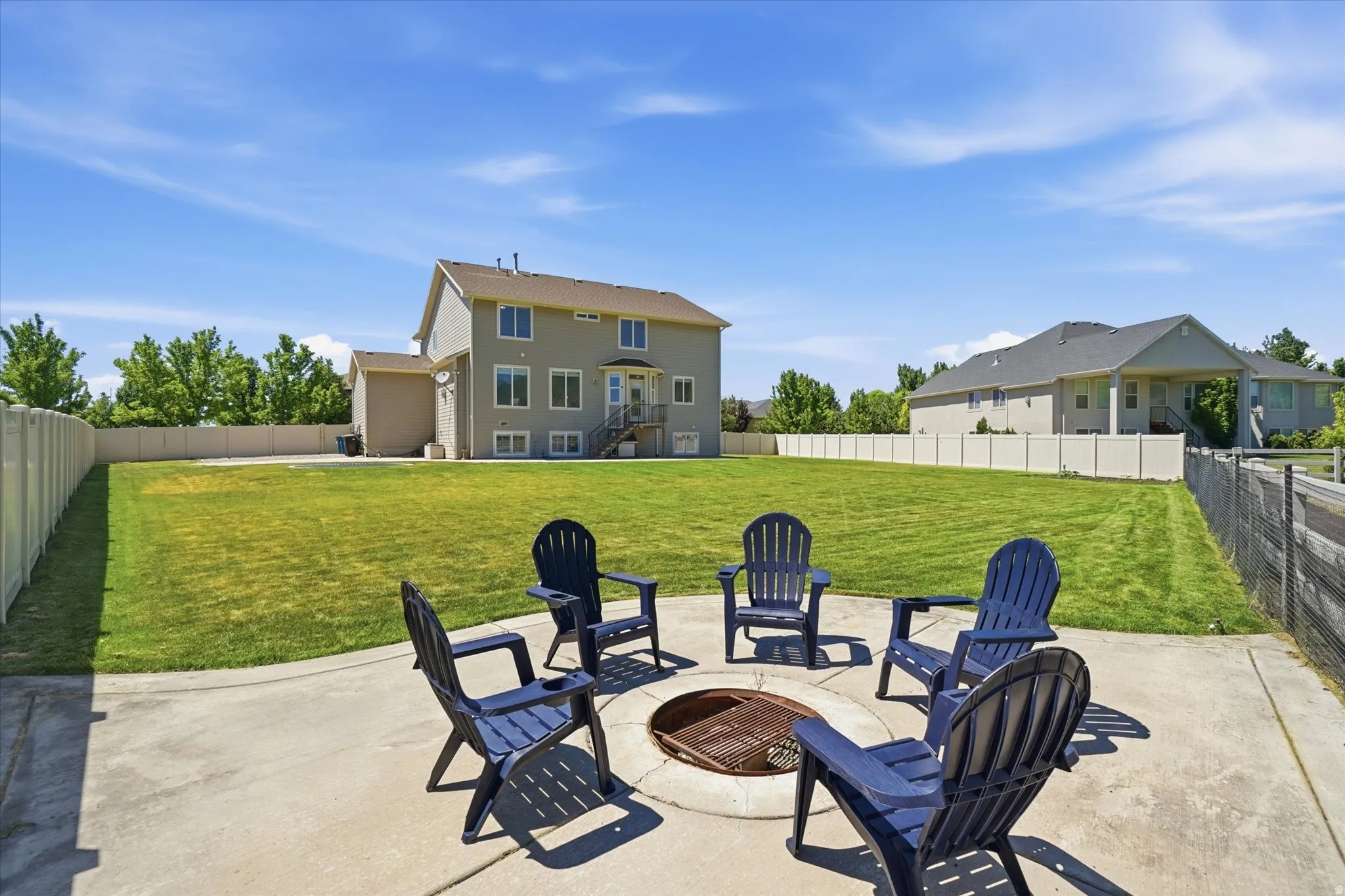 Spacious backyard featuring a concrete patio with a built-in fire pit