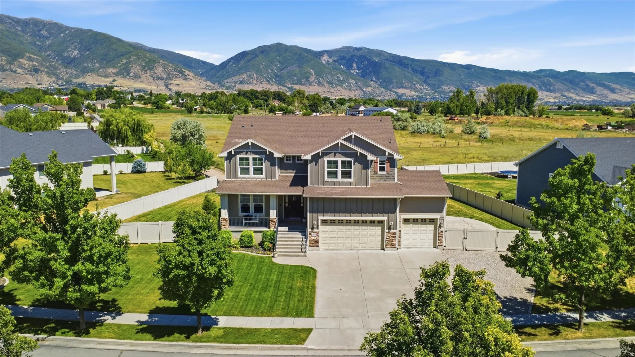 Two-story property featuring a multi-gable roof, a two-car garage, and a covered front porch with stone accents