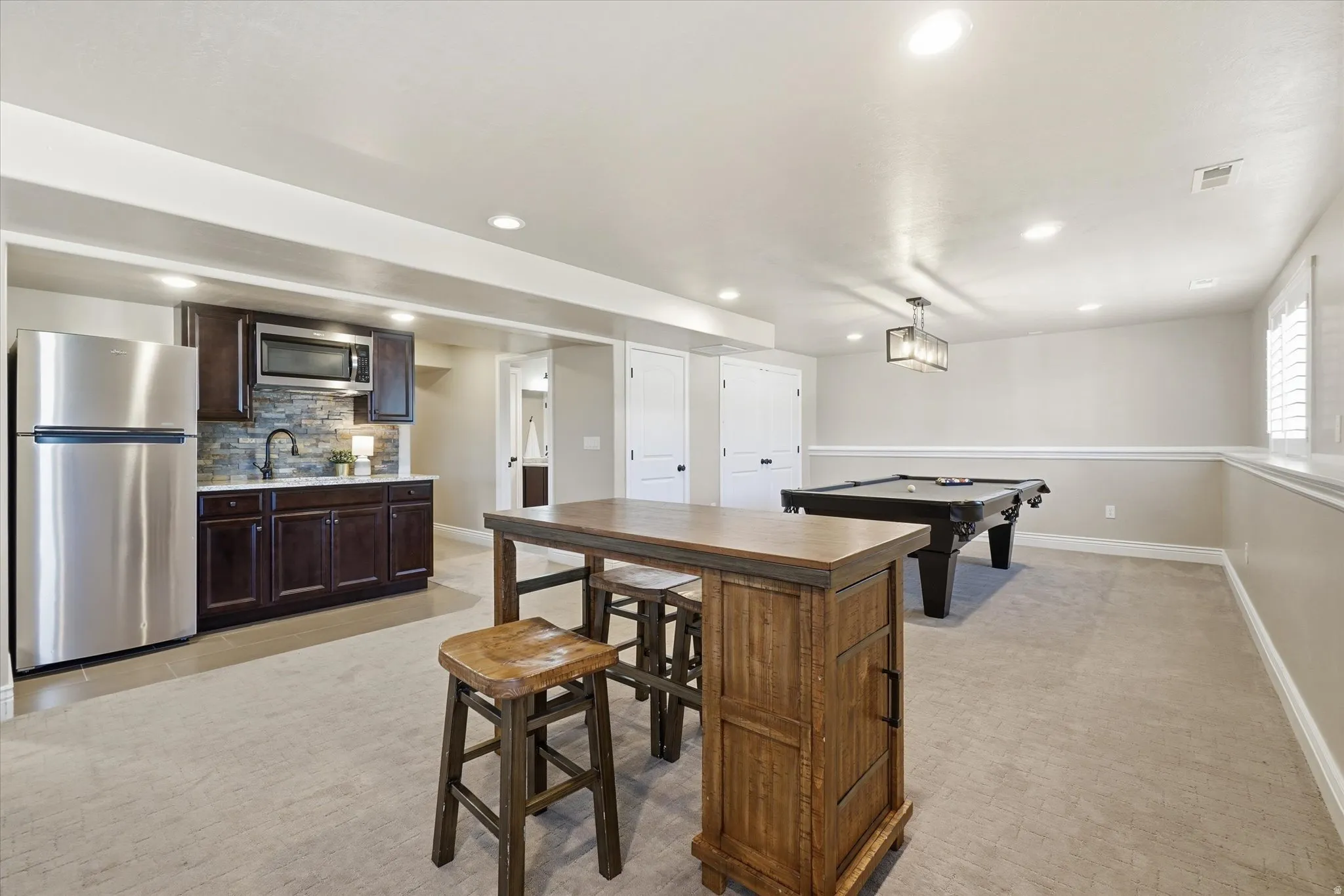 Basement recreation room with kitchenette and ample storage.