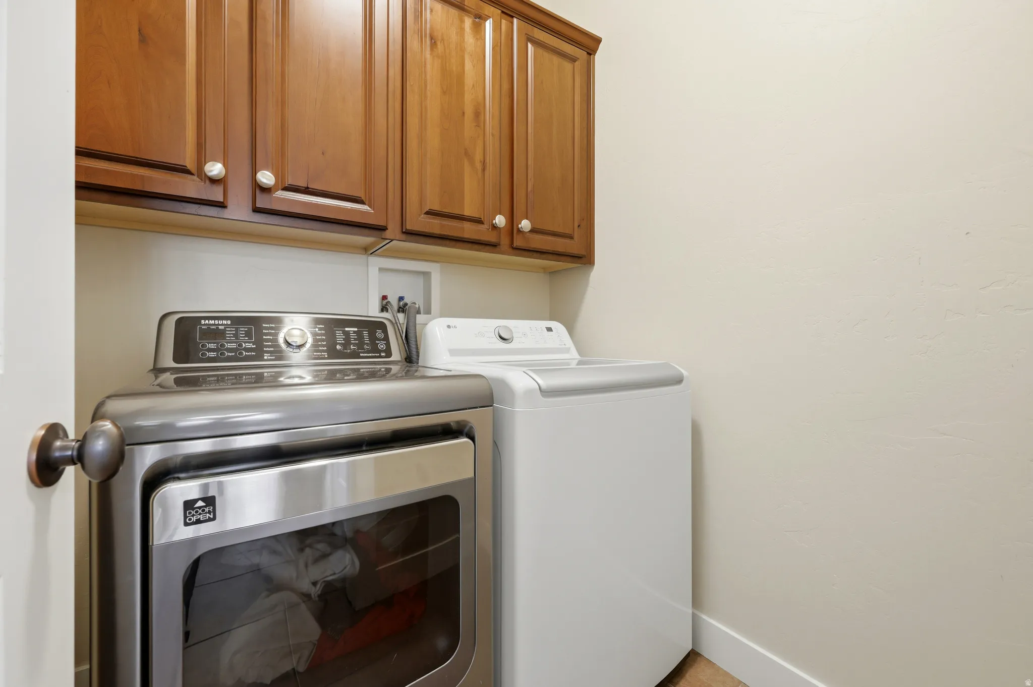 Laundry area featuring upper cabinetry with wood-finish doors and brushed nickel hardware