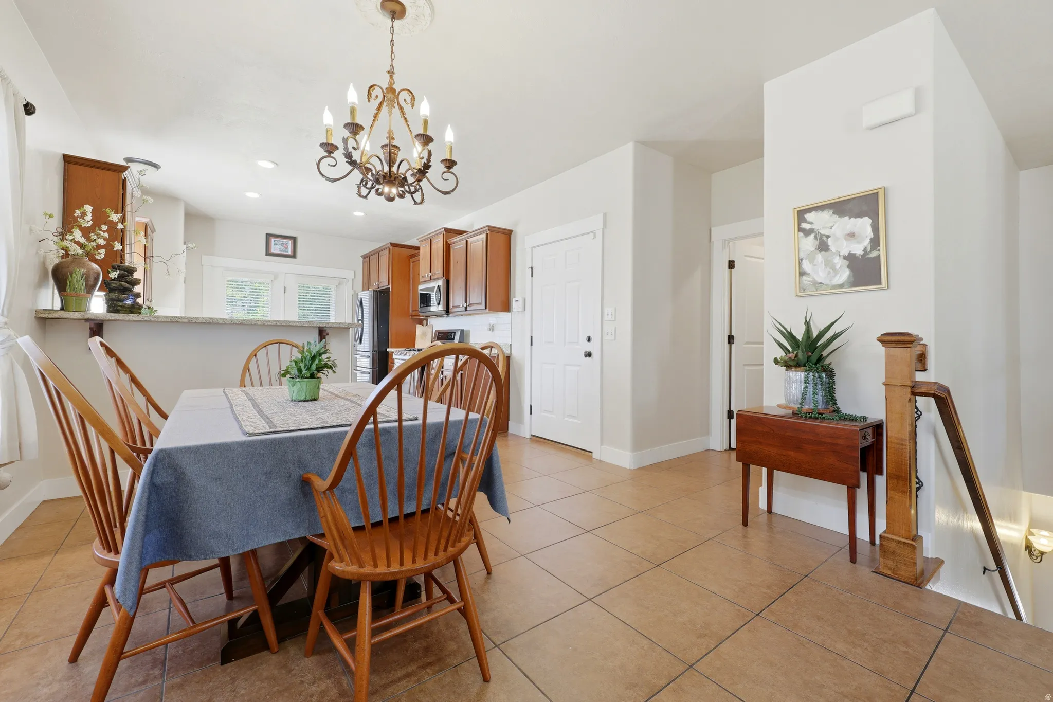 Dining area featuring a central chandelier, tiled flooring, and a breakfast bar counter