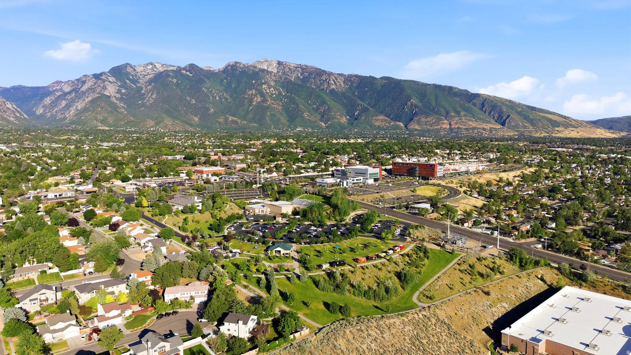 Expansive aerial perspective showcasing a mountainous backdrop, verdant landscapes, and a mix of residential and commercial structures