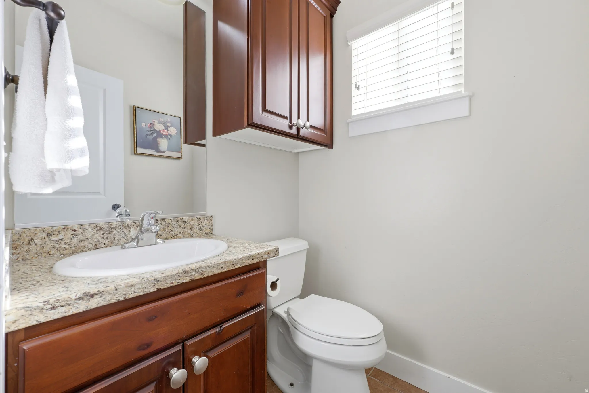 Bathroom vanity featuring a granite countertop, undermount sink, and wood-finish cabinetry
