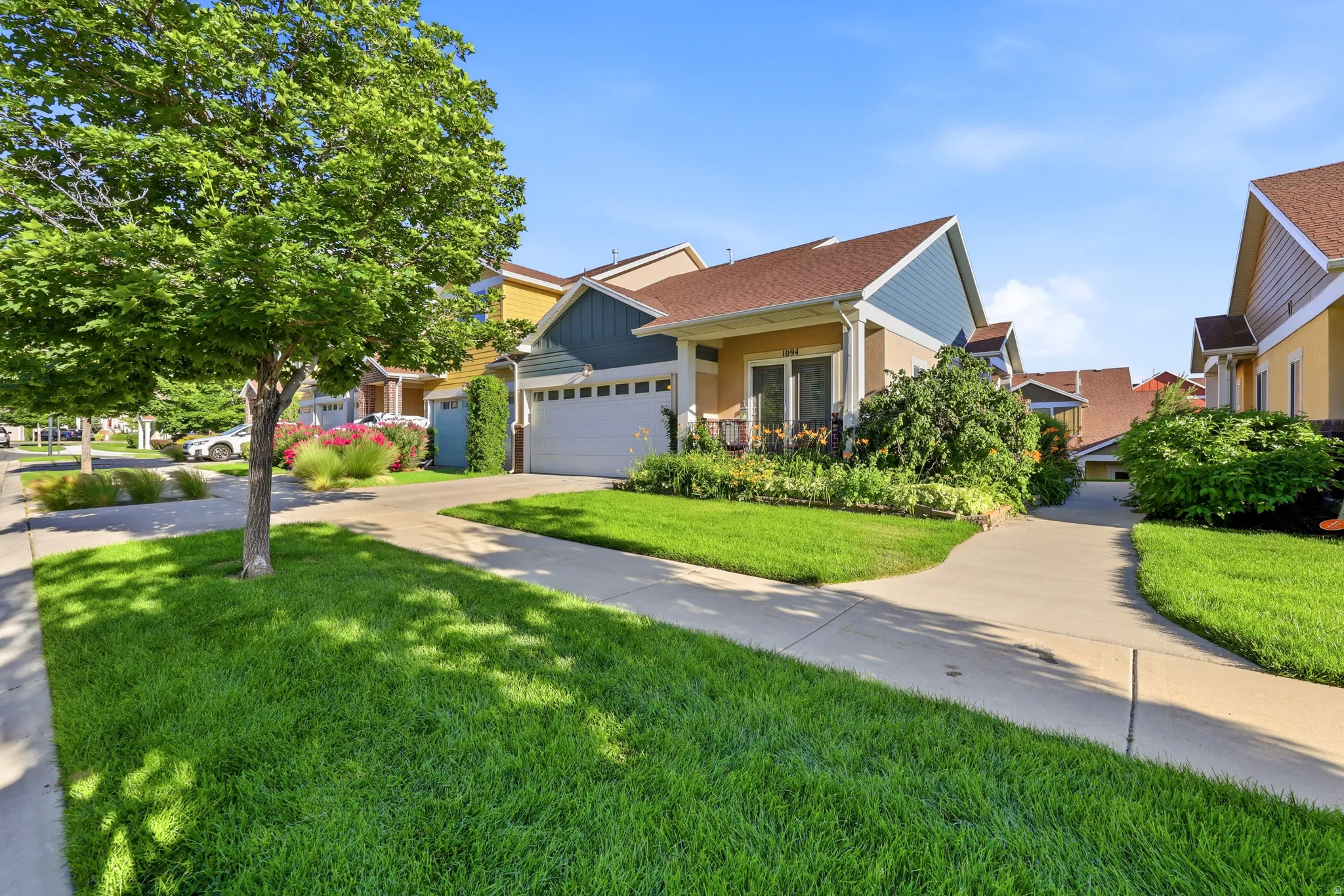 Exterior featuring a two-car garage, covered porch, and mature landscaping