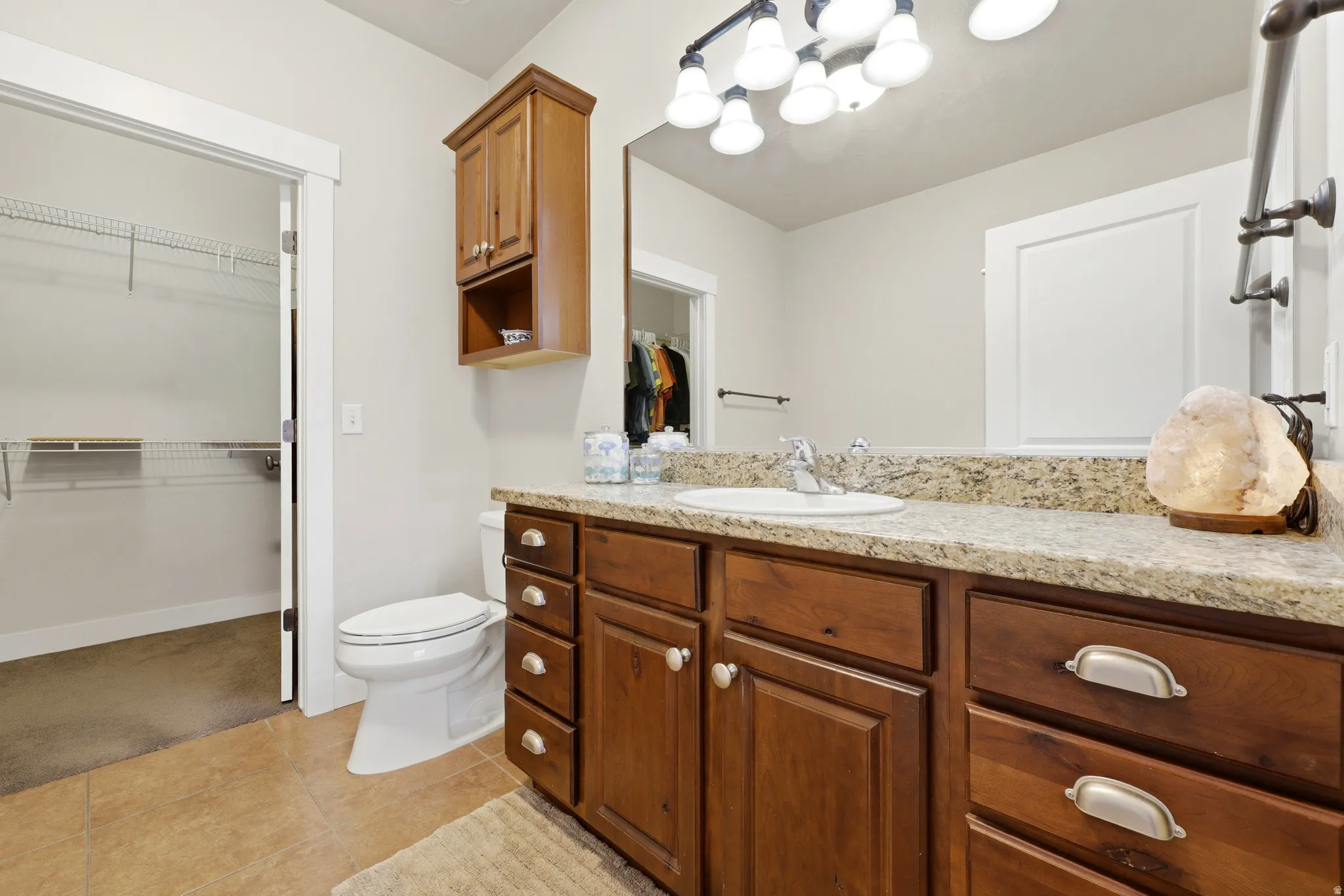 Bathroom featuring a single vanity with wood cabinetry, a granite-look countertop, and an undermount sink