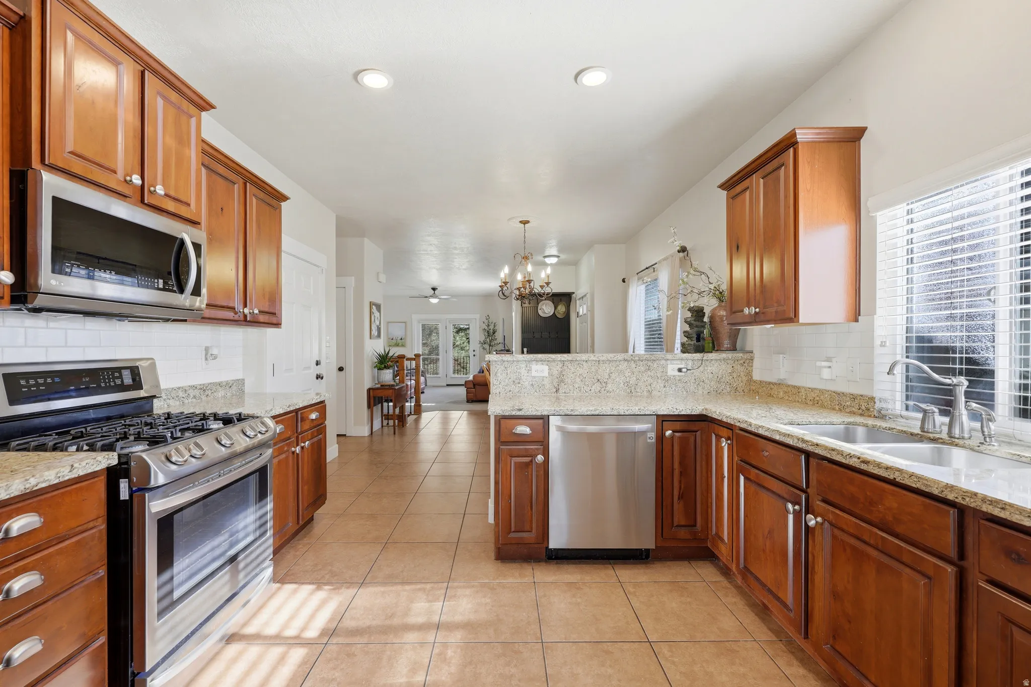 Kitchen featuring wood cabinetry, stainless steel appliances, granite countertops, and a subway tile backsplash