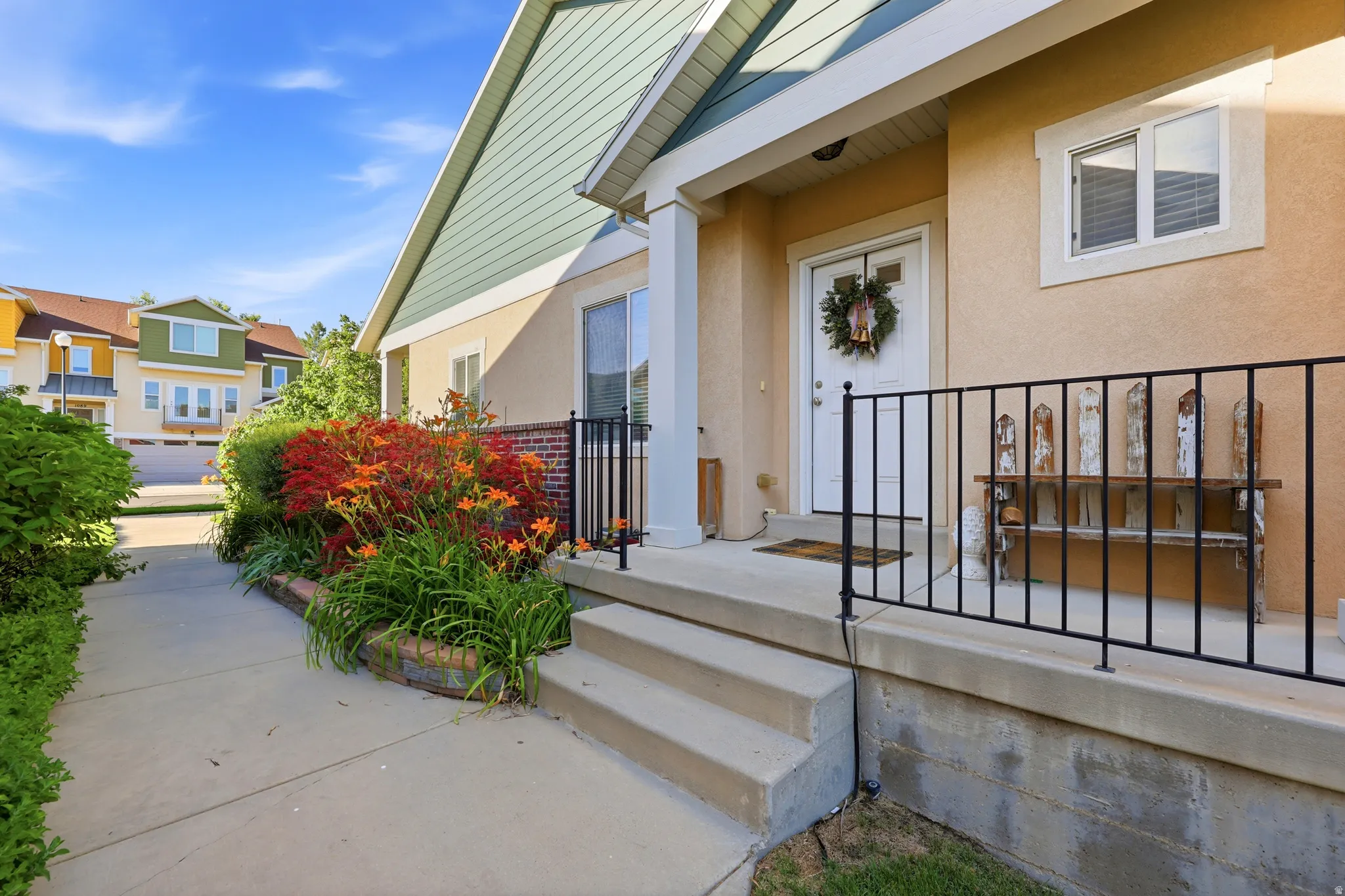 Front entry featuring a concrete porch with black metal railings, a white paneled door, and stucco siding