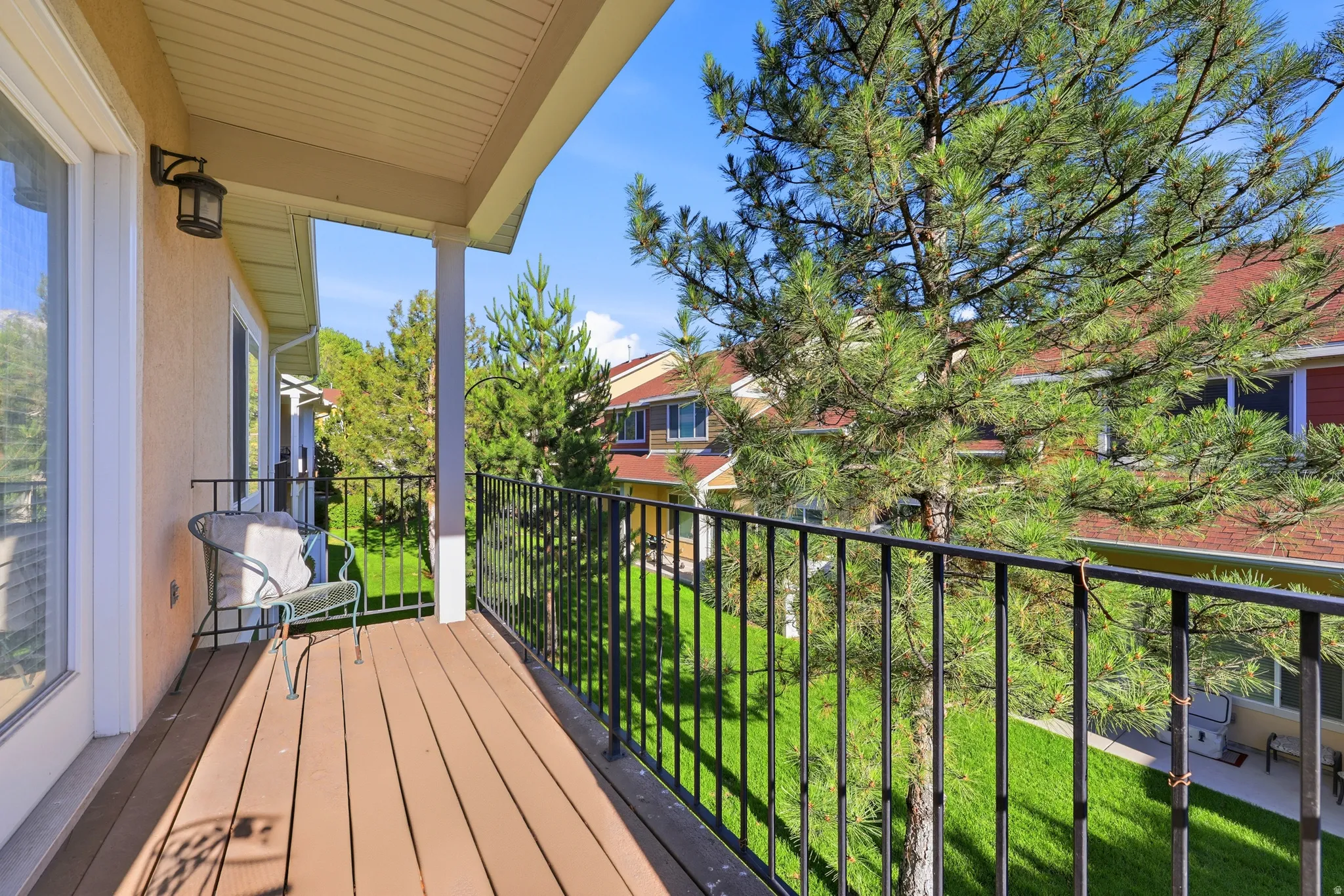 Covered balcony featuring wood-finish flooring, white support columns, and black metal railing