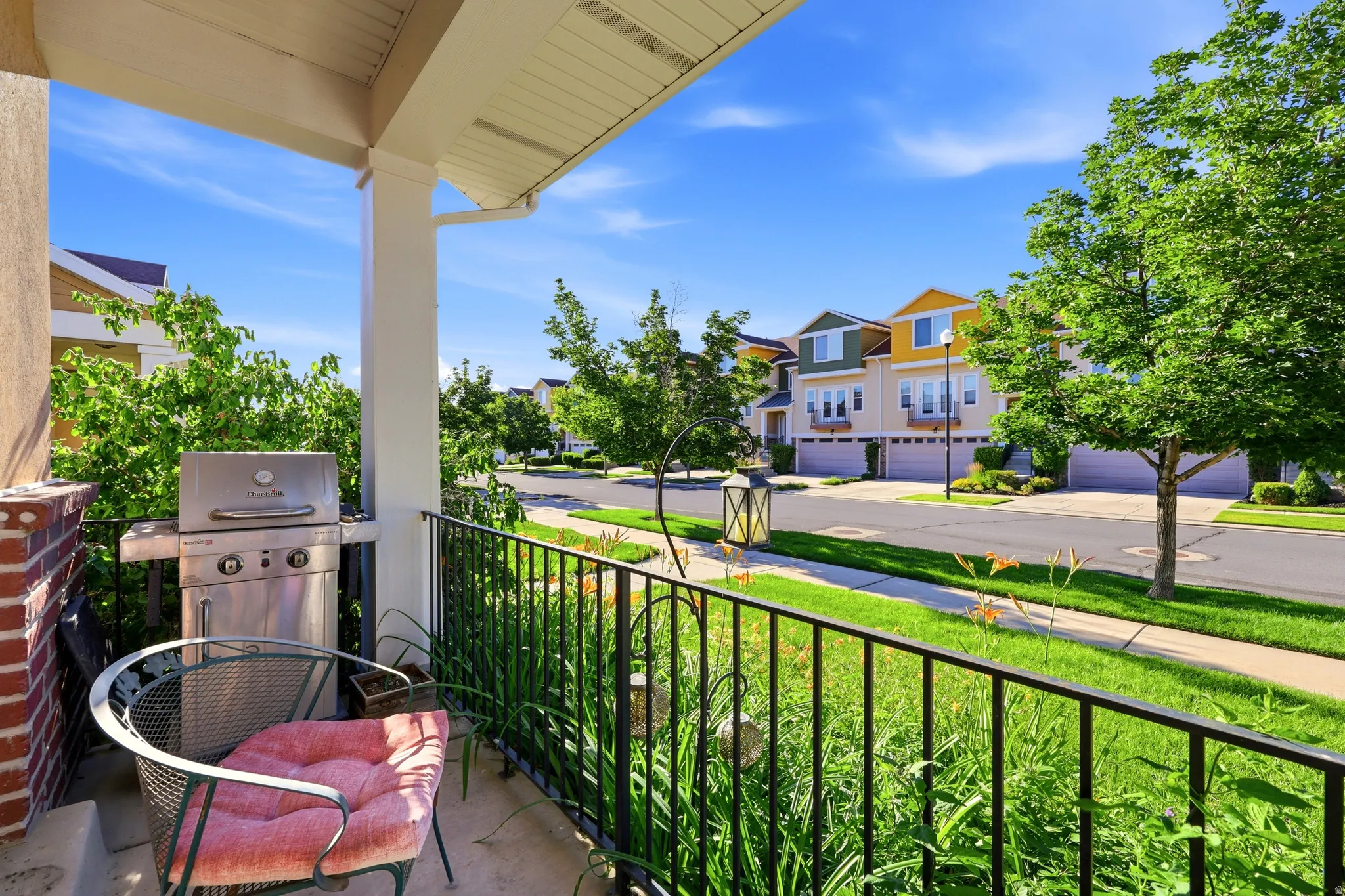 Covered porch featuring a brick column, white overhead ceiling, and black metal railings