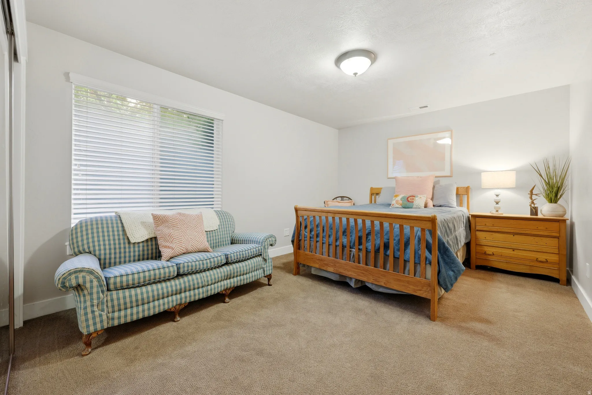 Carpeted room with a large window featuring horizontal blinds