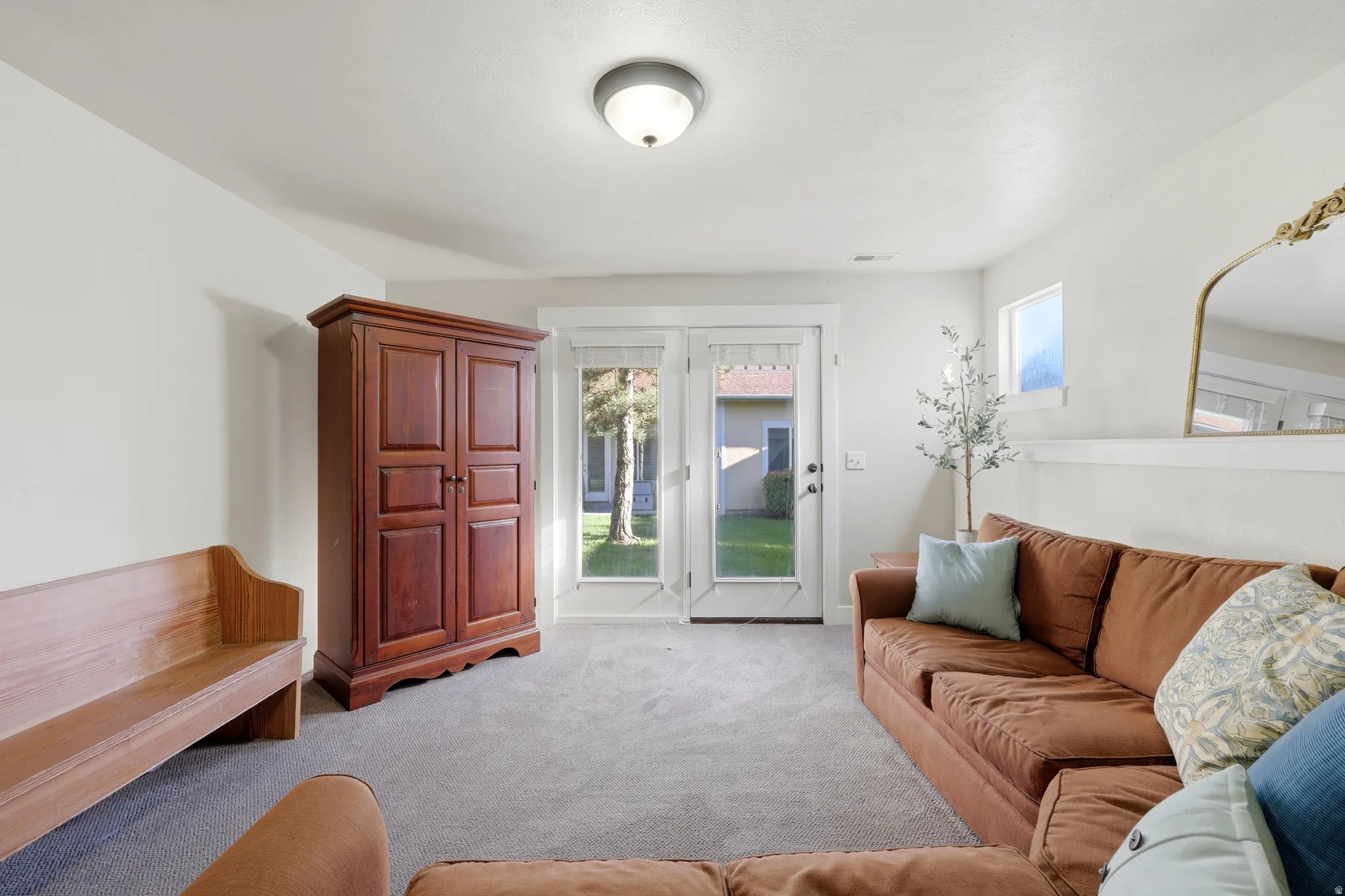 Spacious room featuring light gray carpet, white walls, and a prominent set of white-trimmed French doors