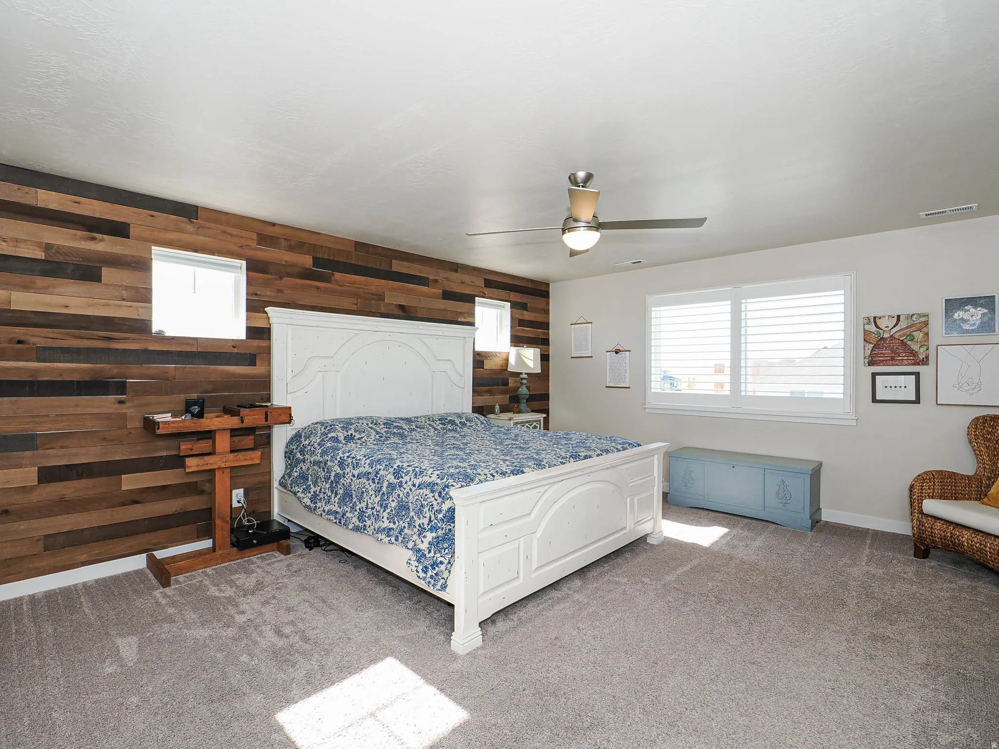 The Primary Bedroom featuring a barn wood-panel accent wall with two integrated windows