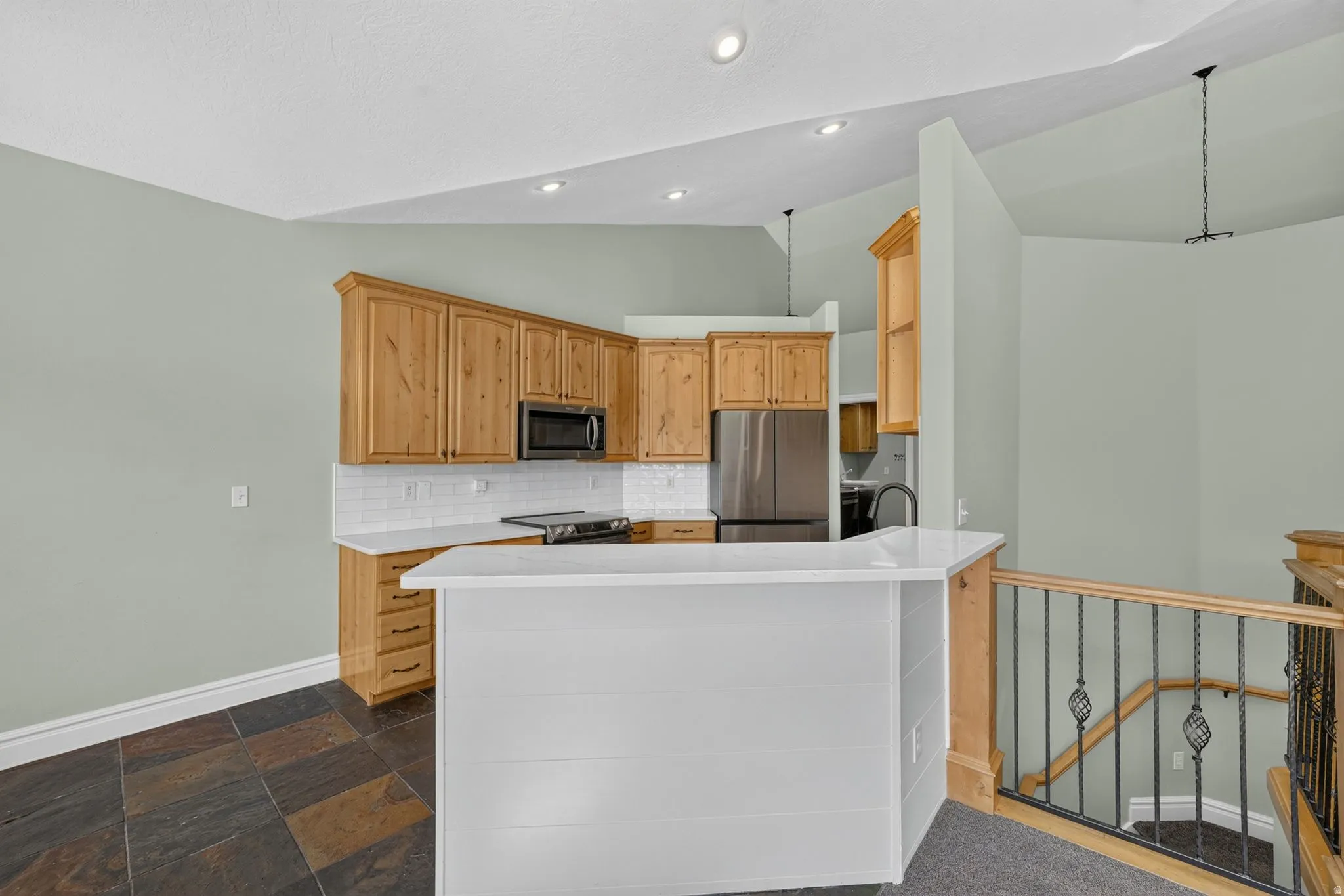 Kitchen area with natural wood cabinetry and white subway tile backsplash