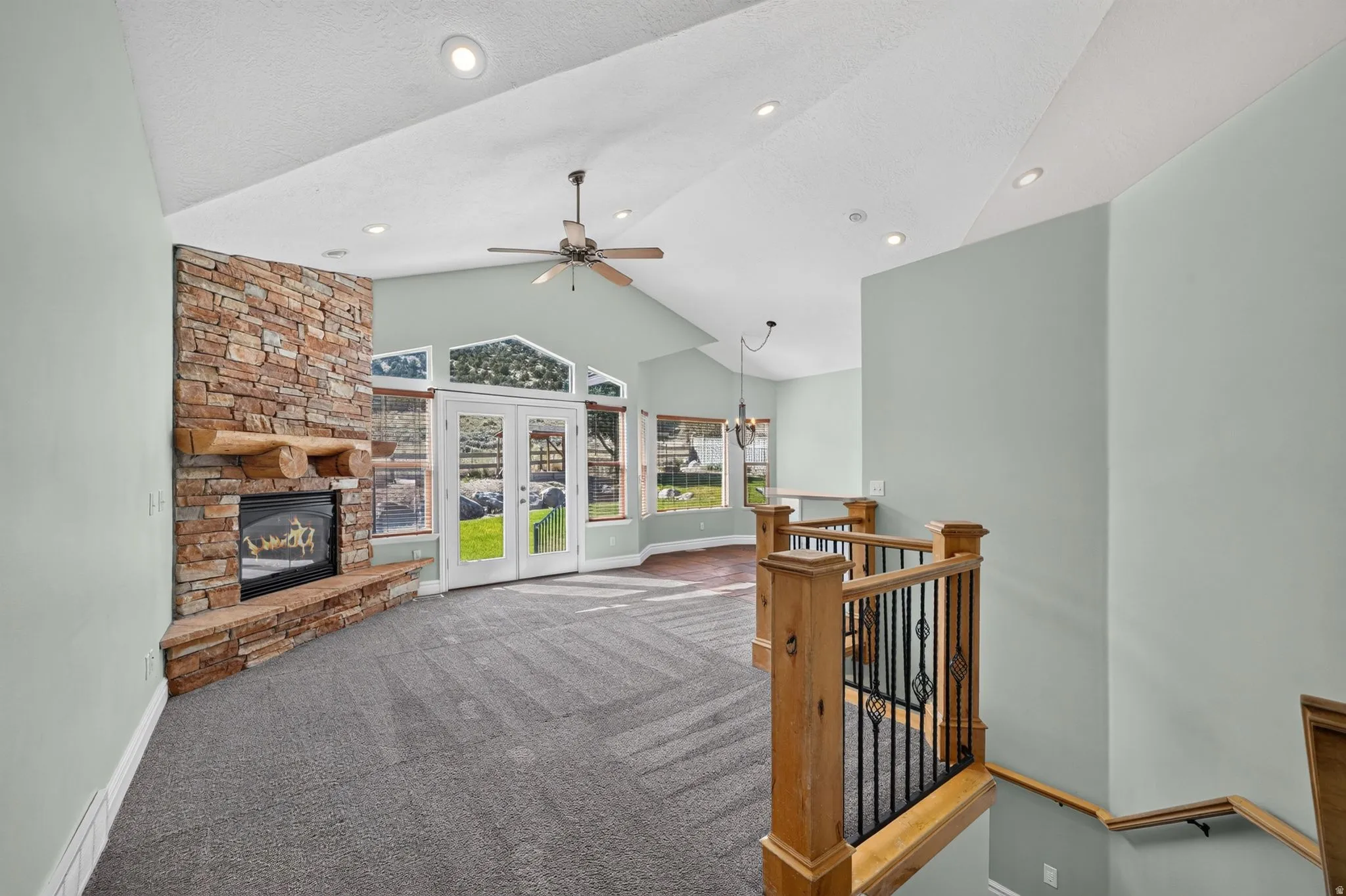 Carpeted interior with a stone-clad fireplace and wood mantle