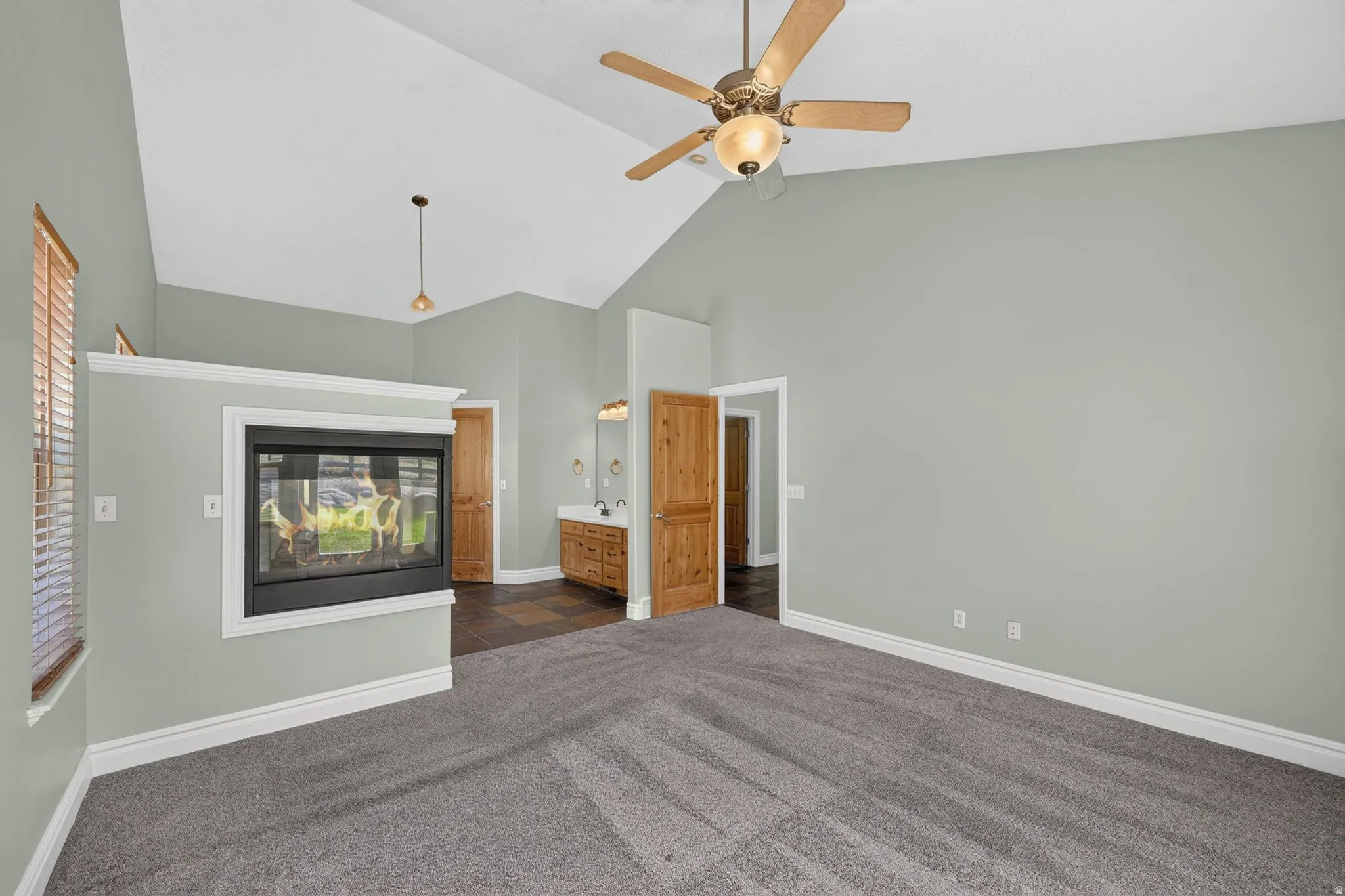 Spacious interior with vaulted ceilings, a built-in fireplace, and a wood-finish ceiling fan