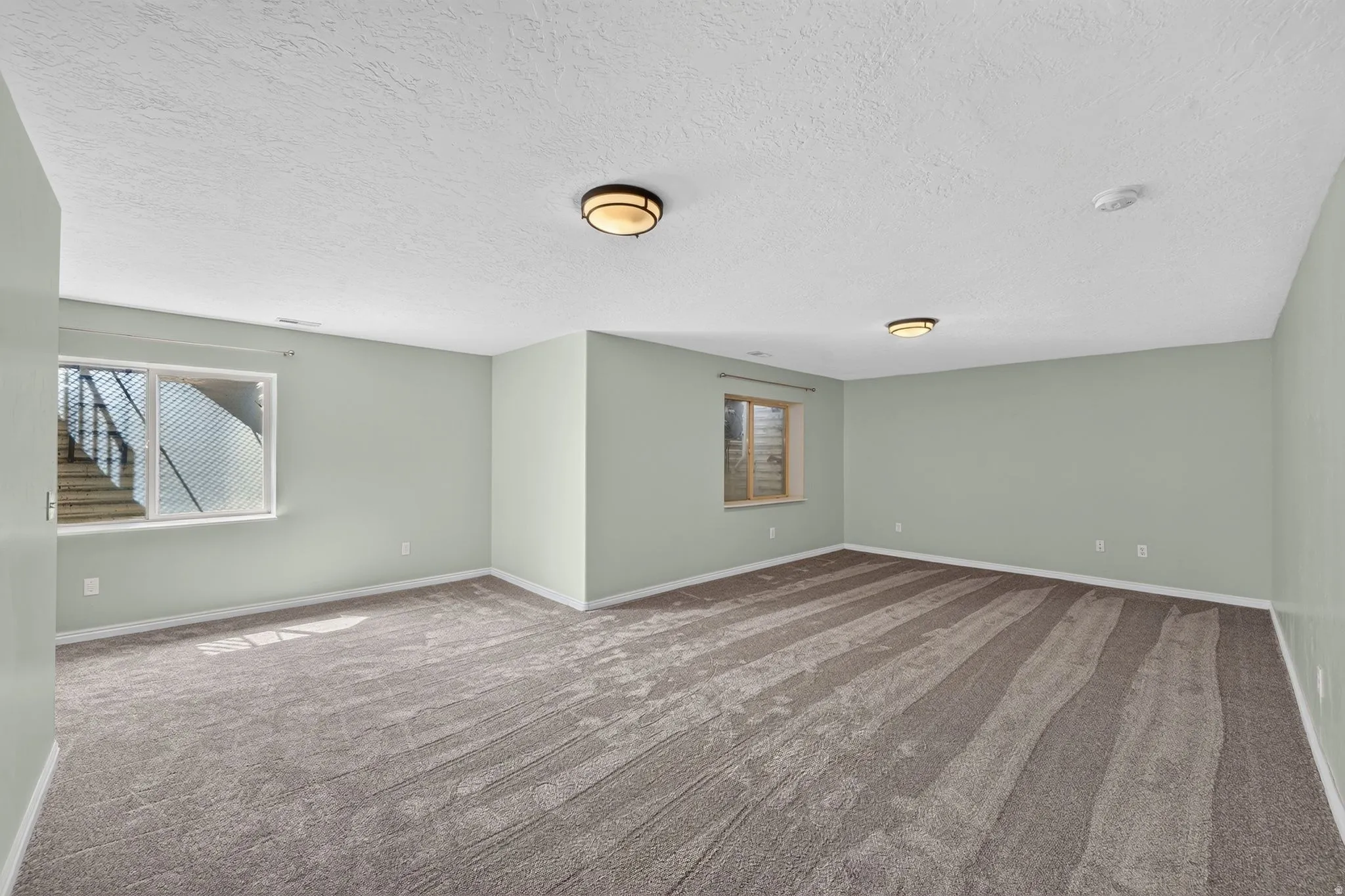 Spacious room featuring new carpeting, two egress windows, and recessed ceiling lighting
