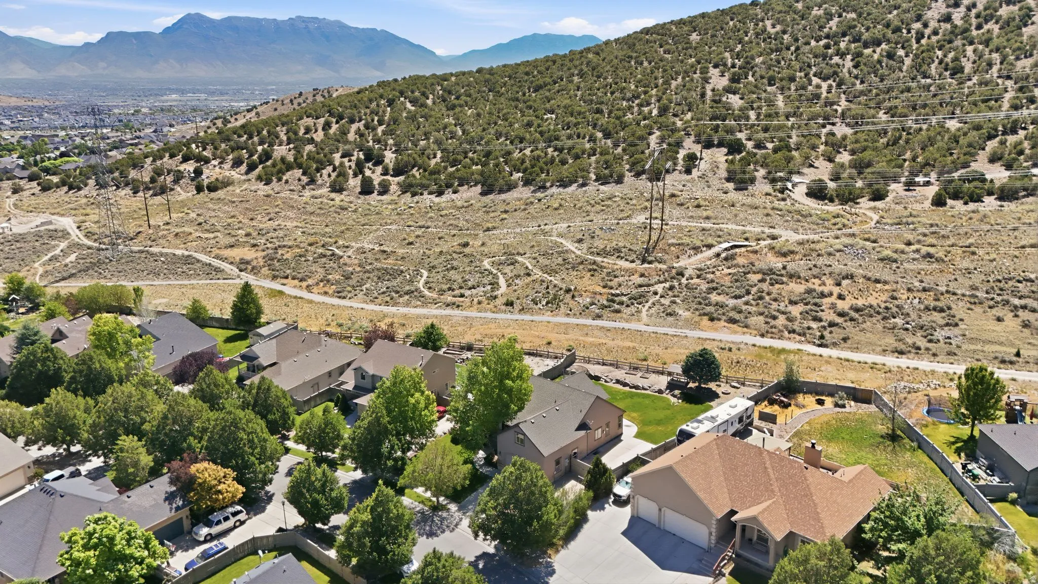Aerial perspective showcasing residential properties bordering an open hillside with established pathways