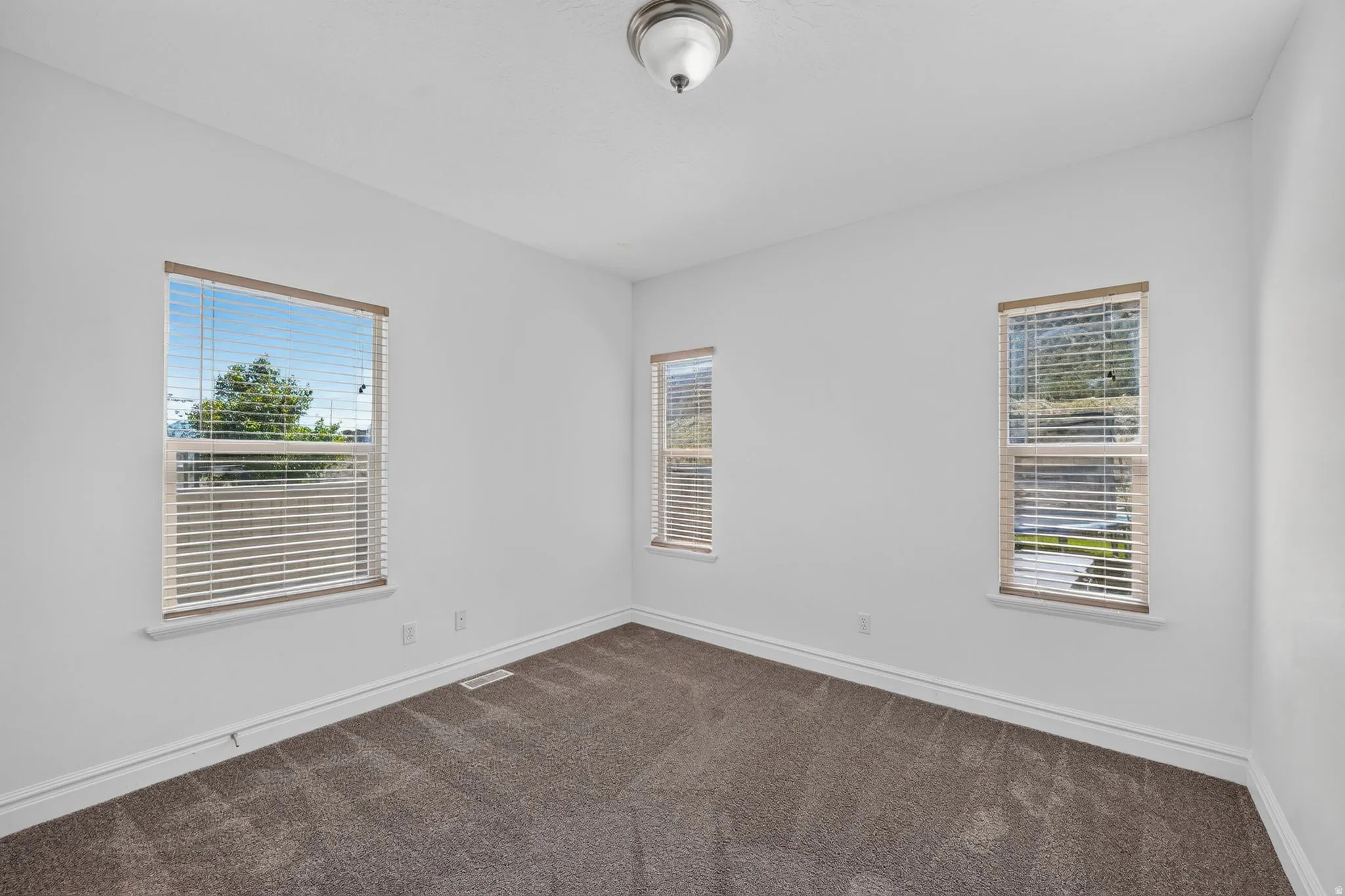 Carpeted room with three windows featuring blinds