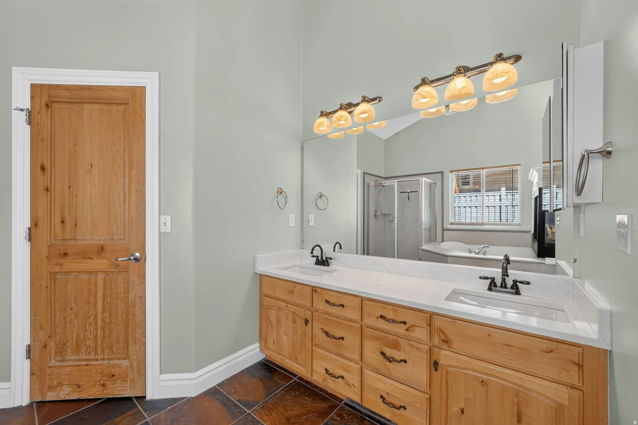 Dual vanity with light wood cabinetry, white countertops, and undermount sinks