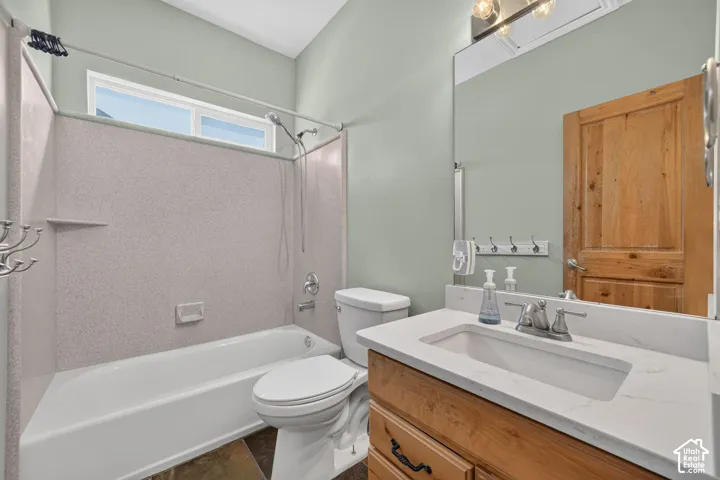 Modern bathroom featuring a white bathtub with a speckled surround, a large vanity with a white countertop and integrated sink, a light wood-finish vanity cabinet, a wall-mounted mirror, and a wood-paneled door