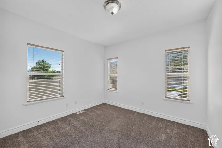 Carpeted room with three windows featuring blinds